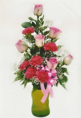 Feminine delicate and dainty this arrangement features the classic rose, standard carnations and gypsophila in a colorful glass vase